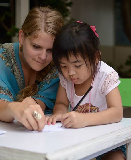 Teach Thailand teacher with student writing at desk