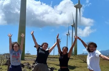 students jump abroad by wind turbines