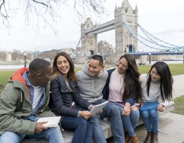 Group of students sitting in front of bridge in London
