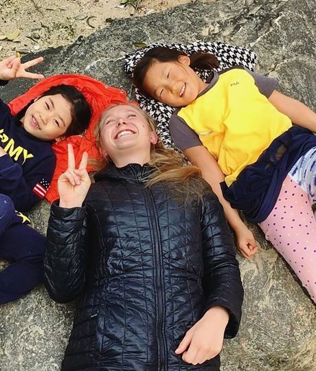Teacher and students laying on the ground smiling