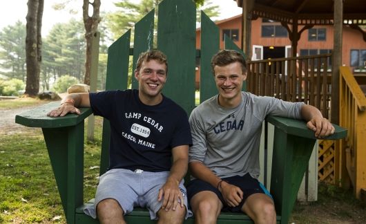 Two summer camp counselors sitting on big green chair