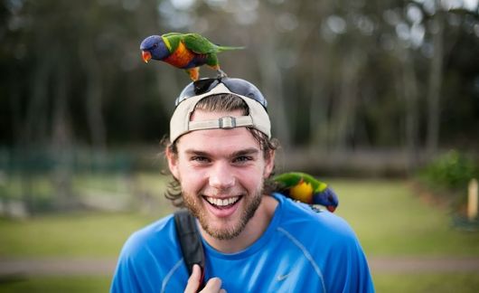Smiling study abroad student with parrot on his head