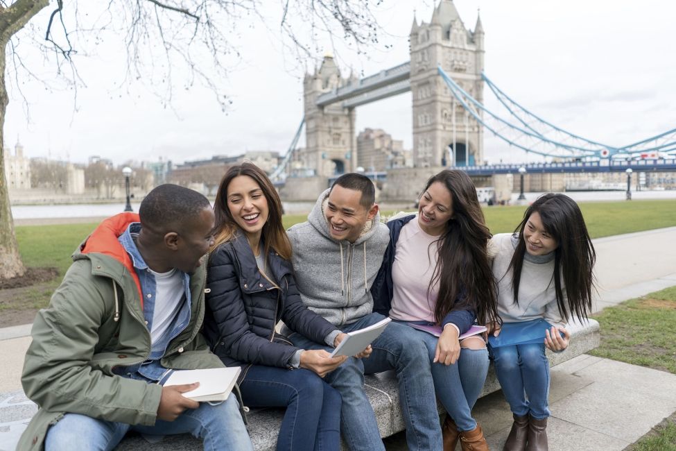 Group of students sitting in front of bridge in London
