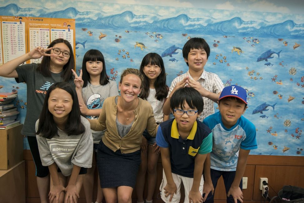 Teacher and students posing in front of ocean mural on wall of classroom
