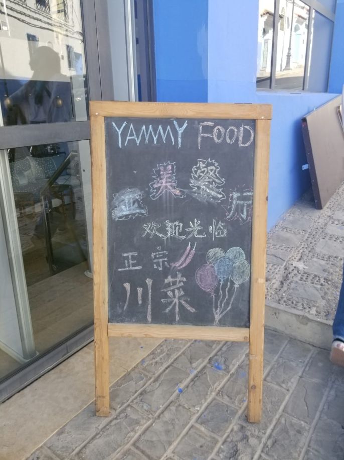 A chalk restaurant advertisement for "Yammy Food," featuring various languages in various scripts.