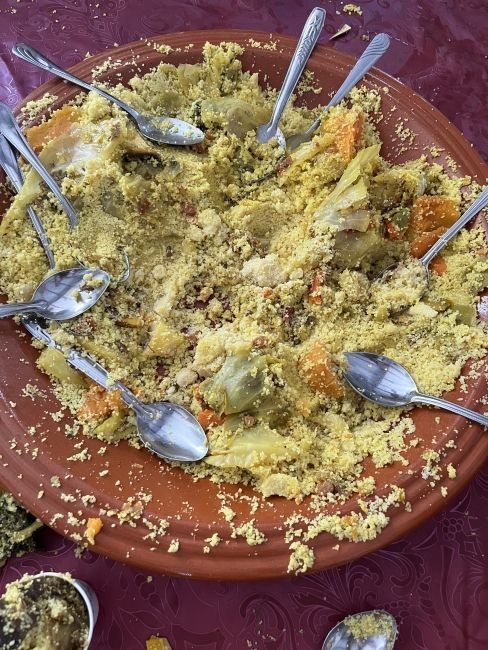 A dish of mostly-eaten couscous with spoons lying around