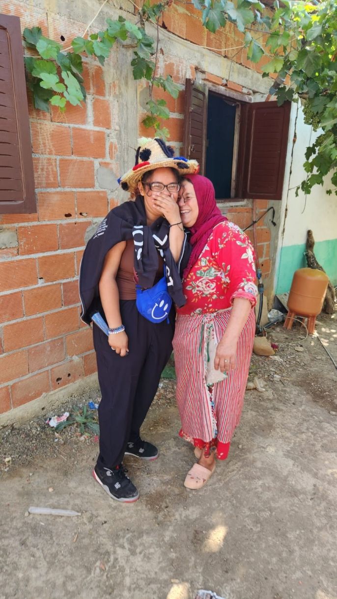 One of the students standing next to a Moroccan woman of the household and smiling