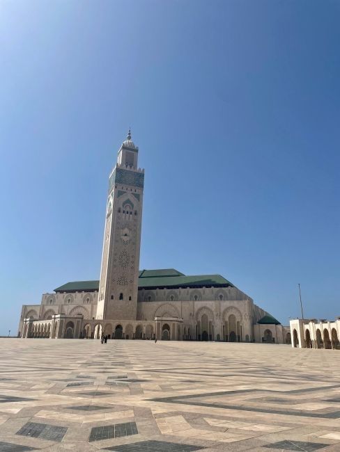 A towering mosque with a mostly-empty plaza on a clear day