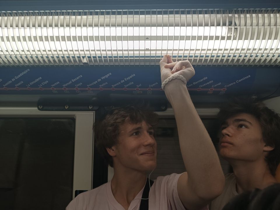 Student holds on to tiny ridge in the lighting in the Madrid metro