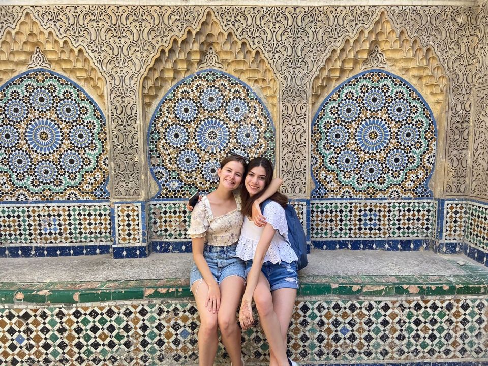 Two female participants posing in front of mosaic tiles in Tangier