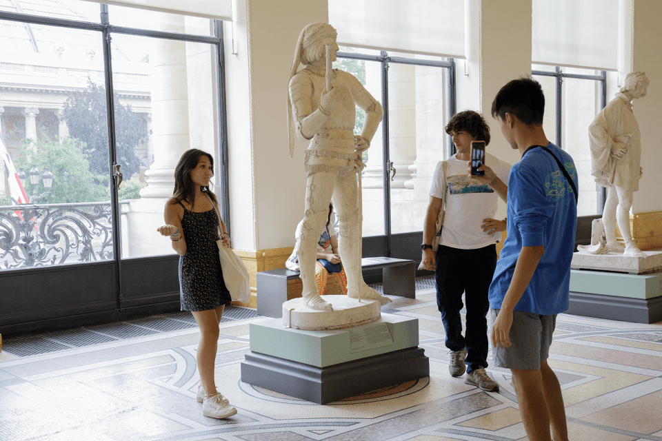 Students posing with statue in Paris art museum