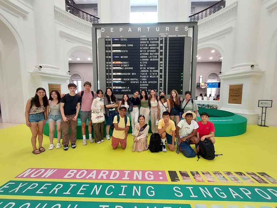 High school students standing in front of departures board in Singapore museum