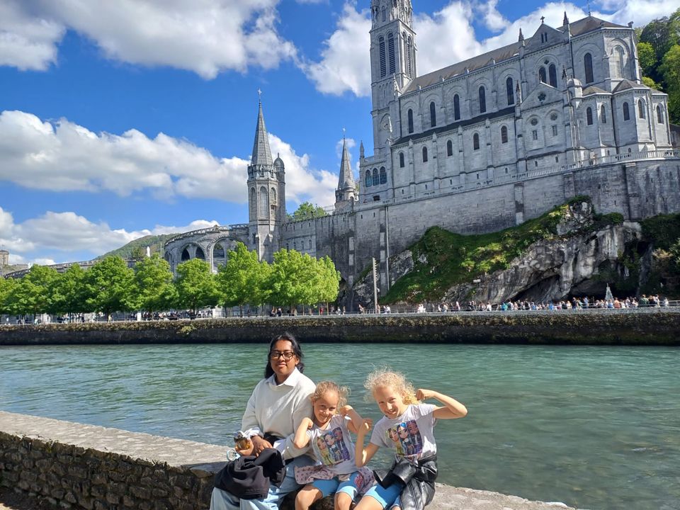 Student with her host sisters sitting by the Seine with Notre Dame behind them