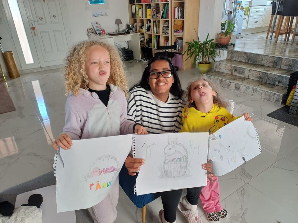 Student with host sisters at Easter holding up pictures of rabbits