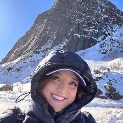 Sophia smiling in front of Reinebringen, a mountain in Northern Norway.