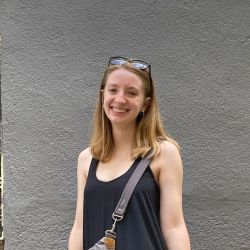 Me, Rose, standing in front of a wall wearing a black dress and some sunglasses on top of my head!