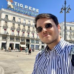 Sam in Madrid with sunglasses and striped shirt.