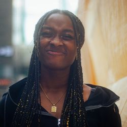 Girl with black braids and black hoodie smiling at the camera