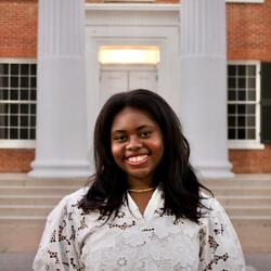 Headshot of Black girl wearing a white shirt and a gold necklace.