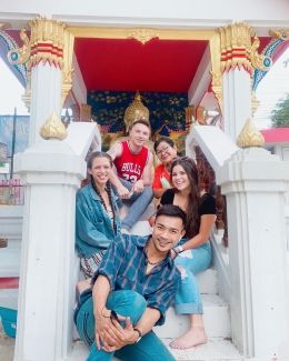 Young people sitting on the steps of a temple in Thailand