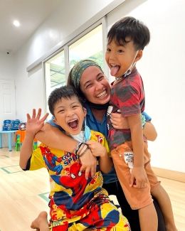 Teacher and students smiling and hugging