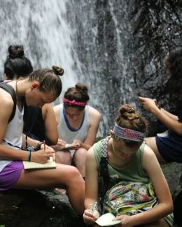 High school students journaling by a waterfall in Monteverde