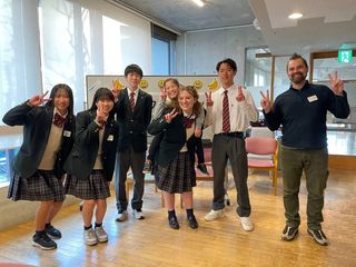 Students and teacher posing in front of whiteboard