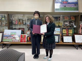 High school exchange student holding up award beside a teacher in Japan