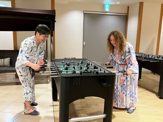 High school student and older man playing foosball