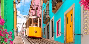 a yellow tram car going downhill in lisbon