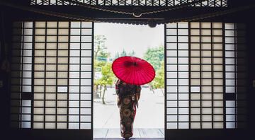 Woman in kimono with umbrella standing in doorway