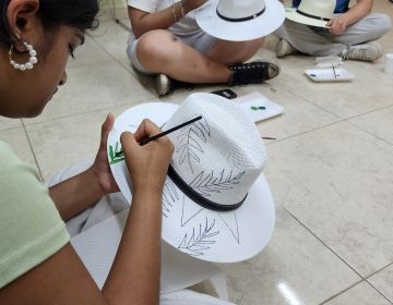 Student painting a hat