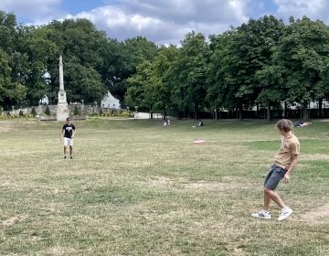 Two boys play frisbee in the park