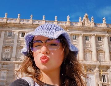 A young woman in a purple hat posing in front of the Royal Palace in Madrid, Spain