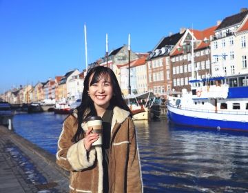 Student posing in front of boats in Copenhagen 