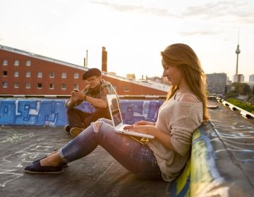 Young woman on laptop on roof in Berlin