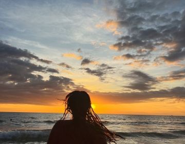 silhouette of a girl against a a sunset over the ocean 