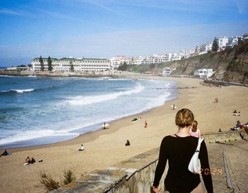 a girl walking down a boardwalk toward a beach