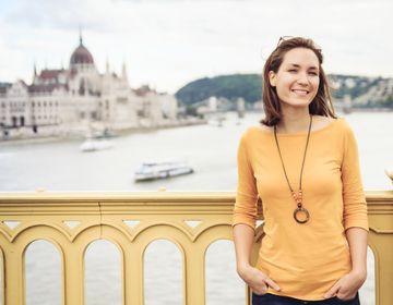 Young woman standing on bridge with parliament in background in Budapest