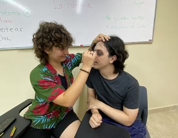 Student helping another one do a face painting.