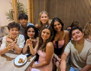 Students sitting at a table with croquettes smile