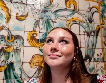 Student next to a tile mural