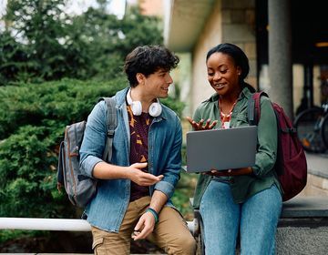 Two students looking at a laptop together on campus