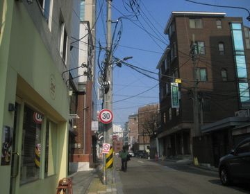 lone street in seoul with so much street wiring visible and one person walking ahead 