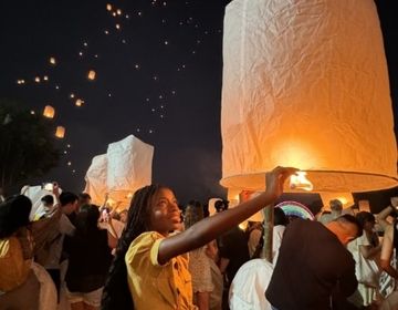 Me holding a lantern with many other lanterns lighting up the sky for the Loy Krathong festival 