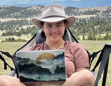 the author sitting with her laptop in the mountains!