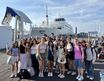 Students stand in front of ferry before boarding 