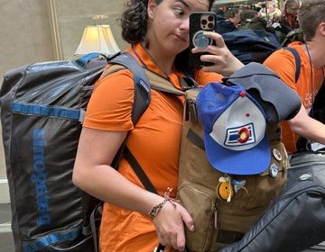 Emiko carrying two backpacks and a guitar in the airport