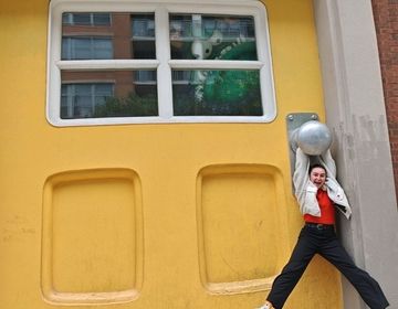 Alizée hangs from the doorknob of the well-known giant yellow door at Big Monster Toys in Chicago.