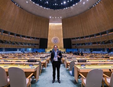 Rodrigue stands in the middle of the United Nations General Assembly Hall.